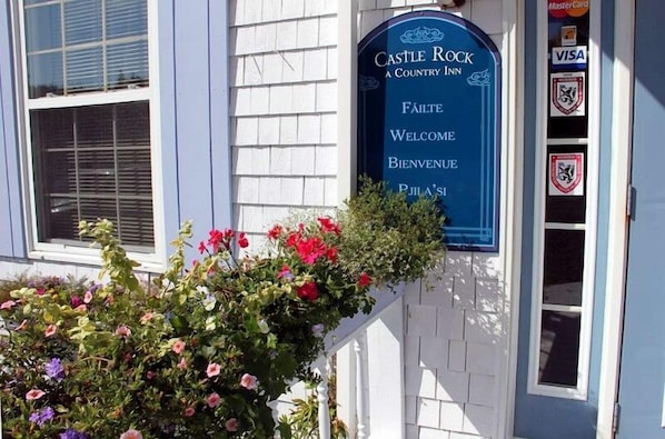A blue sign with "Castle Rock Country Inn" and "Welcome" in multiple languages.