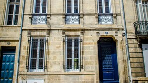Un edificio histórico con una puerta azul, varias ventanas y barandillas de hierro decorativas.