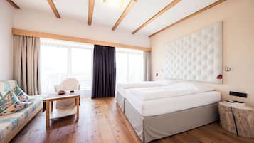 A bedroom with a bed, a sofa, a table, and a large window.