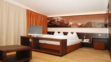 Una habitación de hotel moderna con una cama de madera, un televisor de pantalla plana y un cuadro grande de un paisaje montañoso en la pared.
