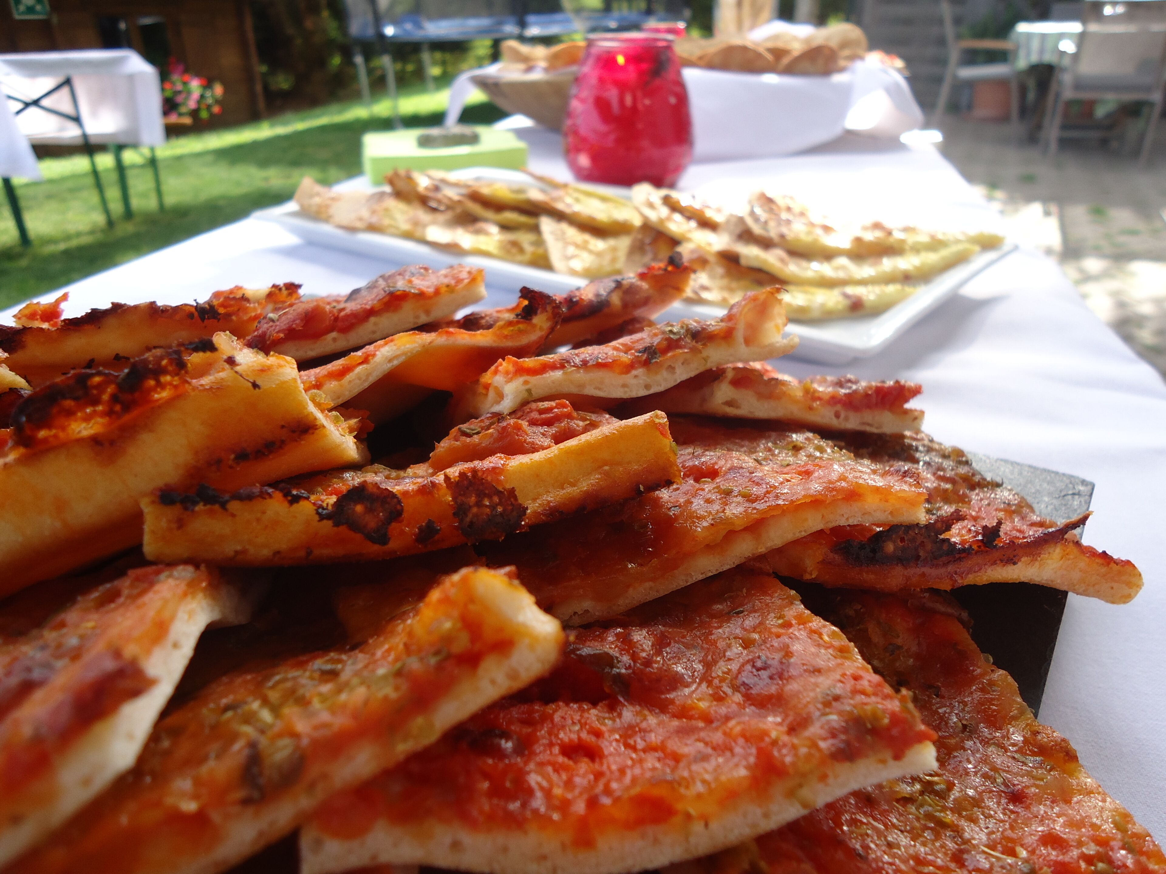 Een tafel met diverse soorten eten, waaronder pizza en platbrood.