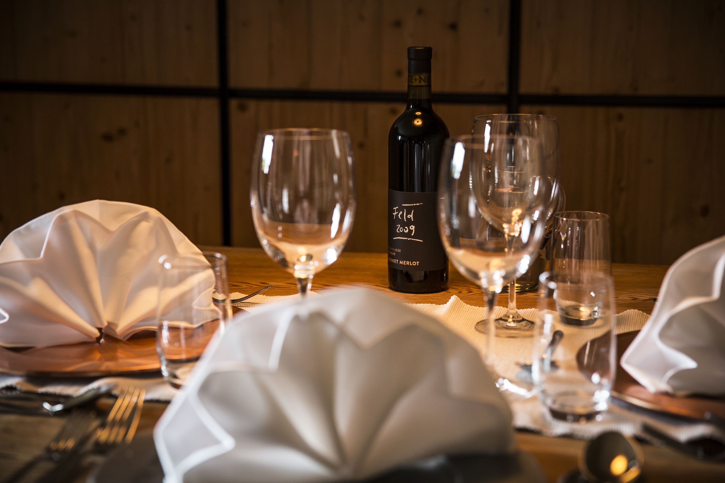 Una mesa servida con copas de vino, una botella y un menú.