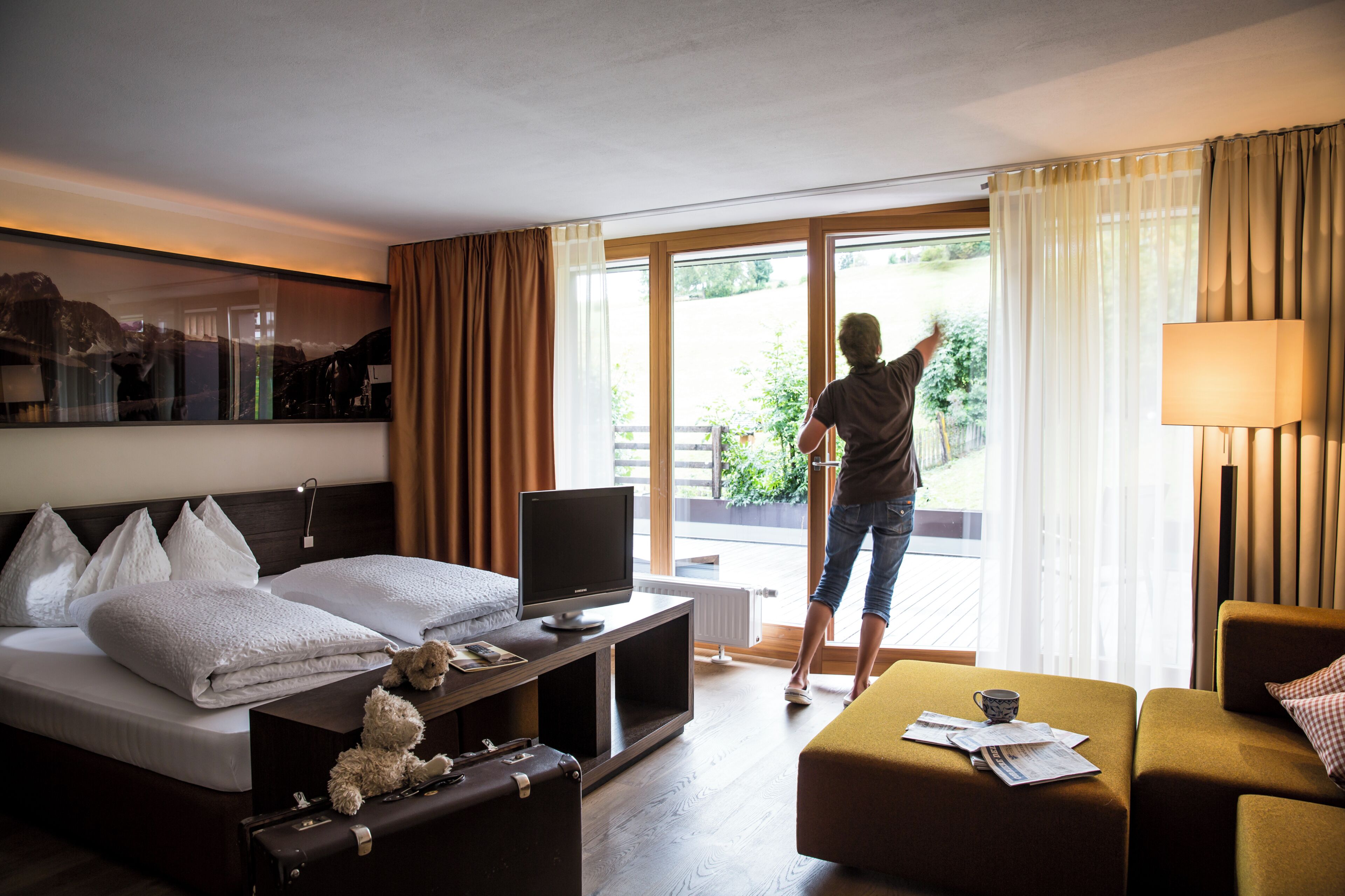 Una habitación de hotel con cama, televisión, escritorio, sofá y ventana con cortinas.