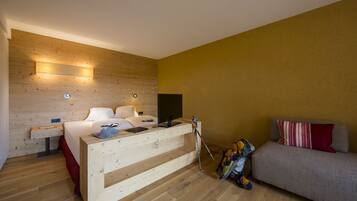 Una habitación de hotel moderna con una cama de madera, un sofá, un televisor y una mesita de noche de madera.