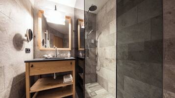 Un baño moderno con tocador de madera, cabina de ducha de vidrio y baldosas de mármol.