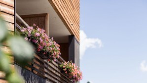 A wooden building with a balcony featuring flower boxes. - Hotel Dolomitenblick (Terento)