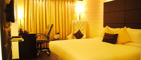 Una habitación de hotel con una cama grande, un escritorio con una silla, un televisor y una lámpara.