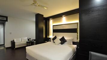 Una habitación de hotel moderna con una cama grande, un sofá, un escritorio y un ventilador de techo.