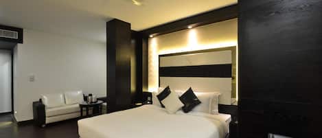 Una habitación de hotel moderna con una cama grande, un sofá, un escritorio y un ventilador de techo.