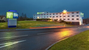 A Holiday Inn Express hotel with a modern design, featuring a flat roof and a large parking lot. - Holiday Inn Express Manchester Airport by IHG (Manchester)