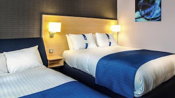 Habitación de hotel con dos camas, cada una con cabecero, lámparas de noche y mesitas de noche.