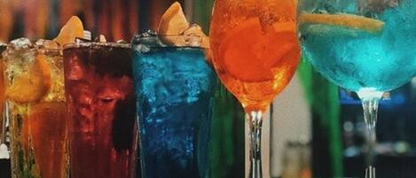 A row of colorful cocktails on a bar counter.
