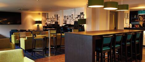 A modern bar area with a long counter, multiple seating options, and a cityscape mural on the wall.