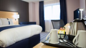 A hotel room with a neatly made bed, a tray with mugs and a kettle, and a window with curtains. - Holiday Inn Express Manchester Airport by IHG (Manchester)