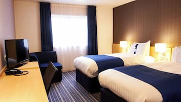 Ein Hotelzimmer mit zwei Betten, einem Schreibtisch mit Fernseher und einem Telefon.