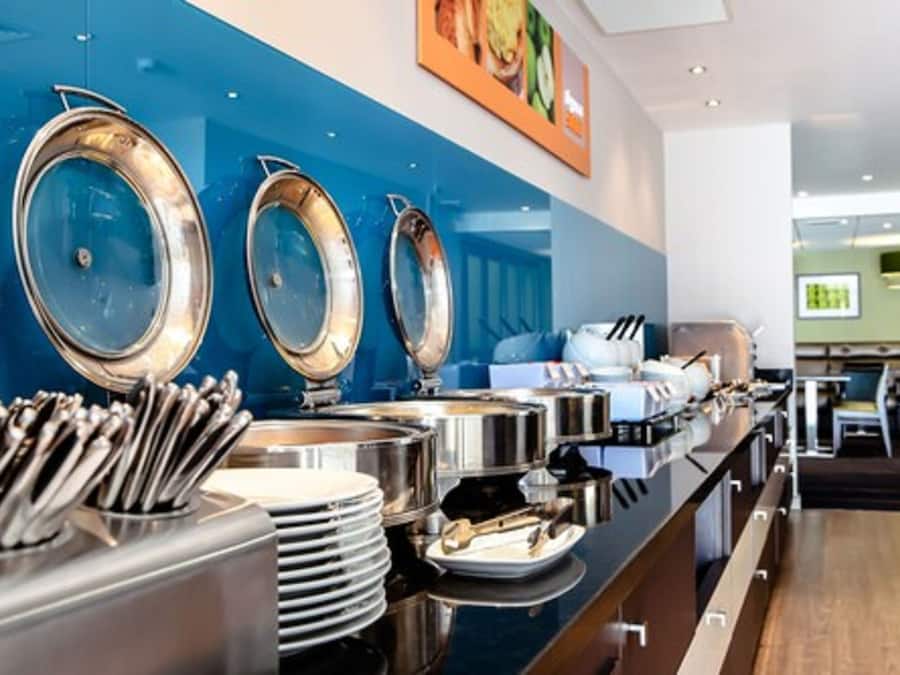 A buffet setup with multiple serving stations, including large metal serving bowls and utensils.