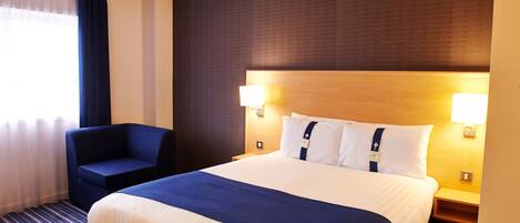 A hotel room with a large bed, two bedside lamps, a chair, and a window with curtains.