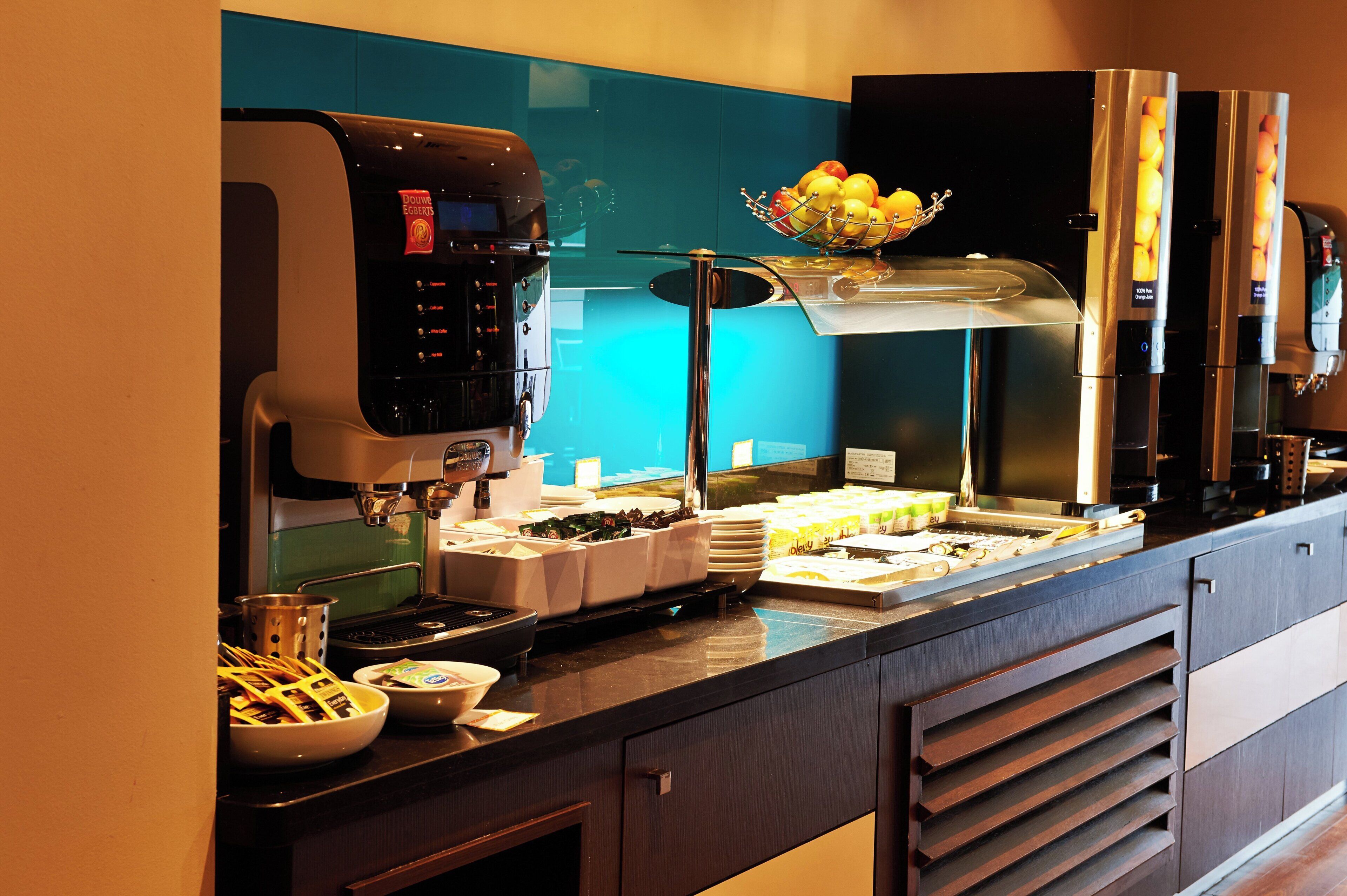 A coffee station with a coffee machine, a fruit bowl, and various coffee containers.