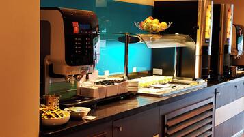 A coffee station with a coffee machine, a fruit bowl, and various coffee containers.