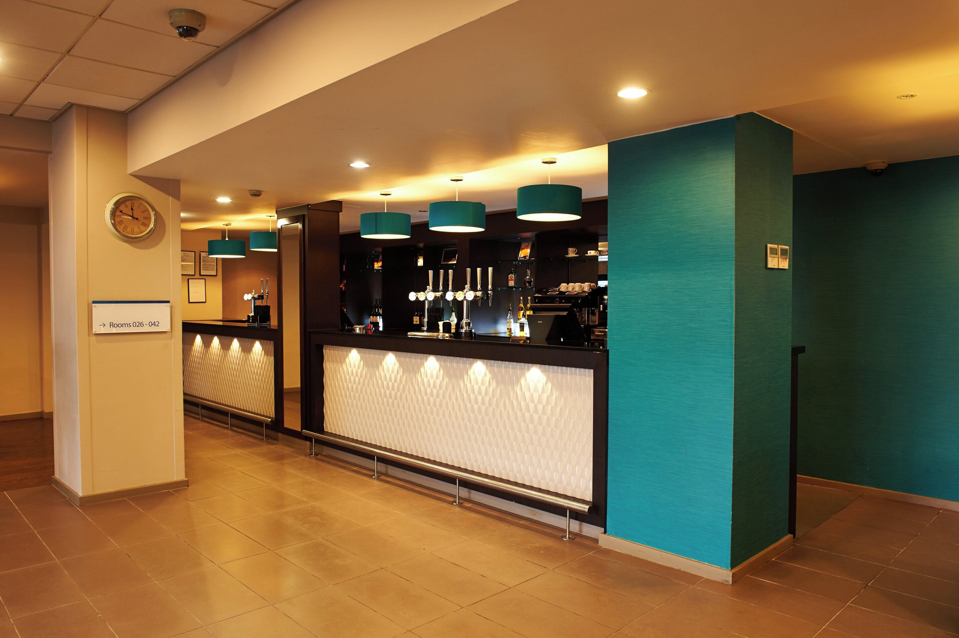 Een hotel receptie met een balie, bar en klok.