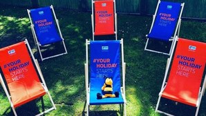 A row of beach chairs with #YOUR HOLIDAY STARTS HERE banners, arranged outdoors. - Holiday Inn Express Manchester Airport by IHG (Manchester)