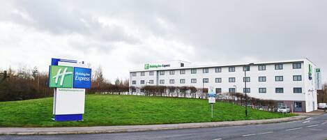 A Holiday Inn Express hotel with a large sign, a parking sign, and a grassy area in front.