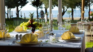 Una mesa dispuesta para una comida con vista al mar, velas blancas y servilletas amarillas.