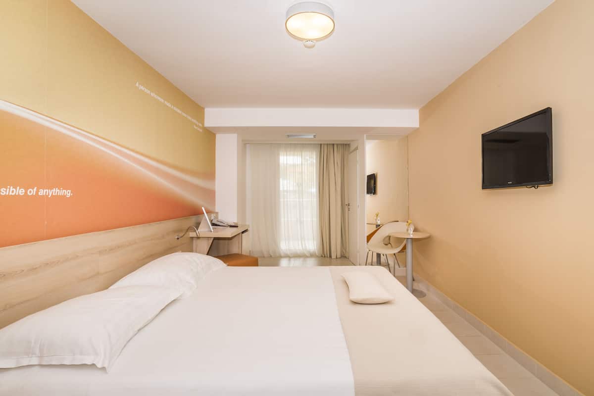 Une chambre d’hôtel comprenant un lit, un bureau, une chaise, une télévision et une salle de bain.