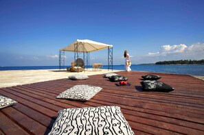 A wooden deck with lounge chairs and a canopy, overlooking a beach. - Residence Umag Plava Laguna (Umag)