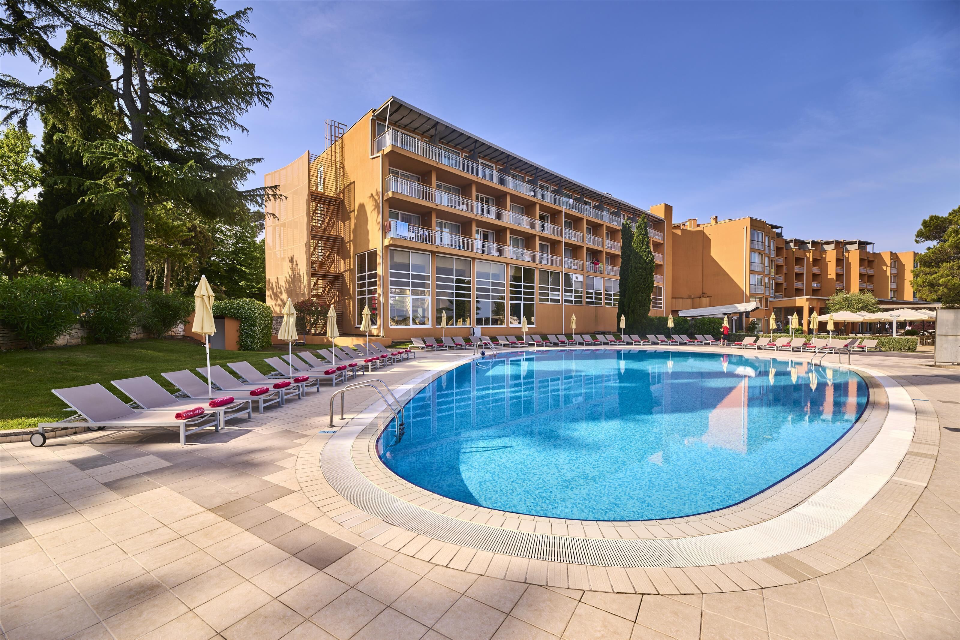 Un hôtel doté d’une grande piscine, de chaises longues et d’un jardin bien entretenu.