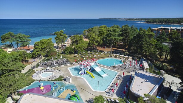 Un complejo turístico frente al mar con varias piscinas, parque acuático y vistas al océano.