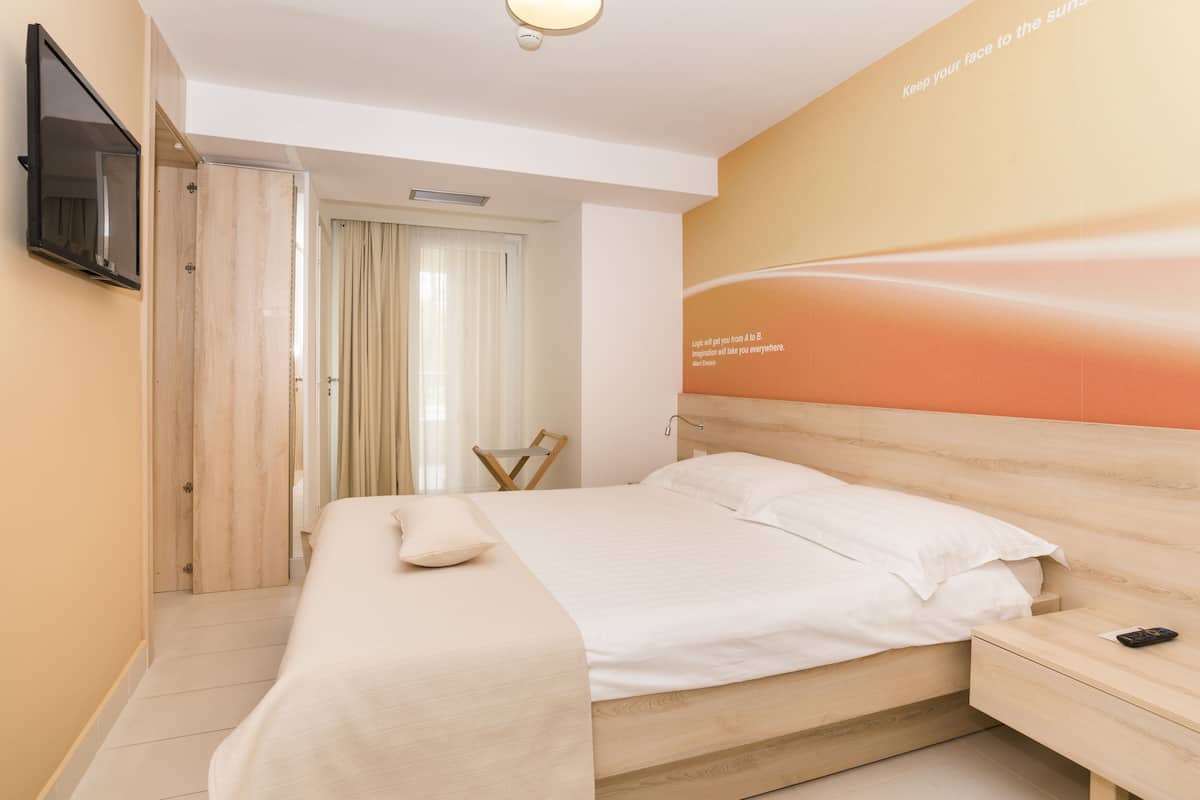 Une chambre d’hôtel équipée d’un lit, d’une table de chevet et d’un téléviseur fixé au mur.