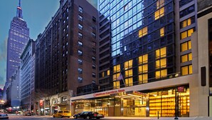 Un Hilton Garden Inn con fachada de vidrio moderna, situado en una ciudad con edificios altos.