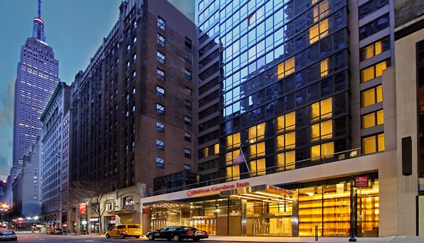 Ein Hilton Garden Inn mit moderner Glasfassade, gelegen in einer Stadt mit hohen Gebäuden.