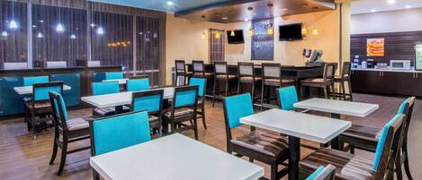 A restaurant with booths and tables, wooden flooring, and a TV mounted on the wall.