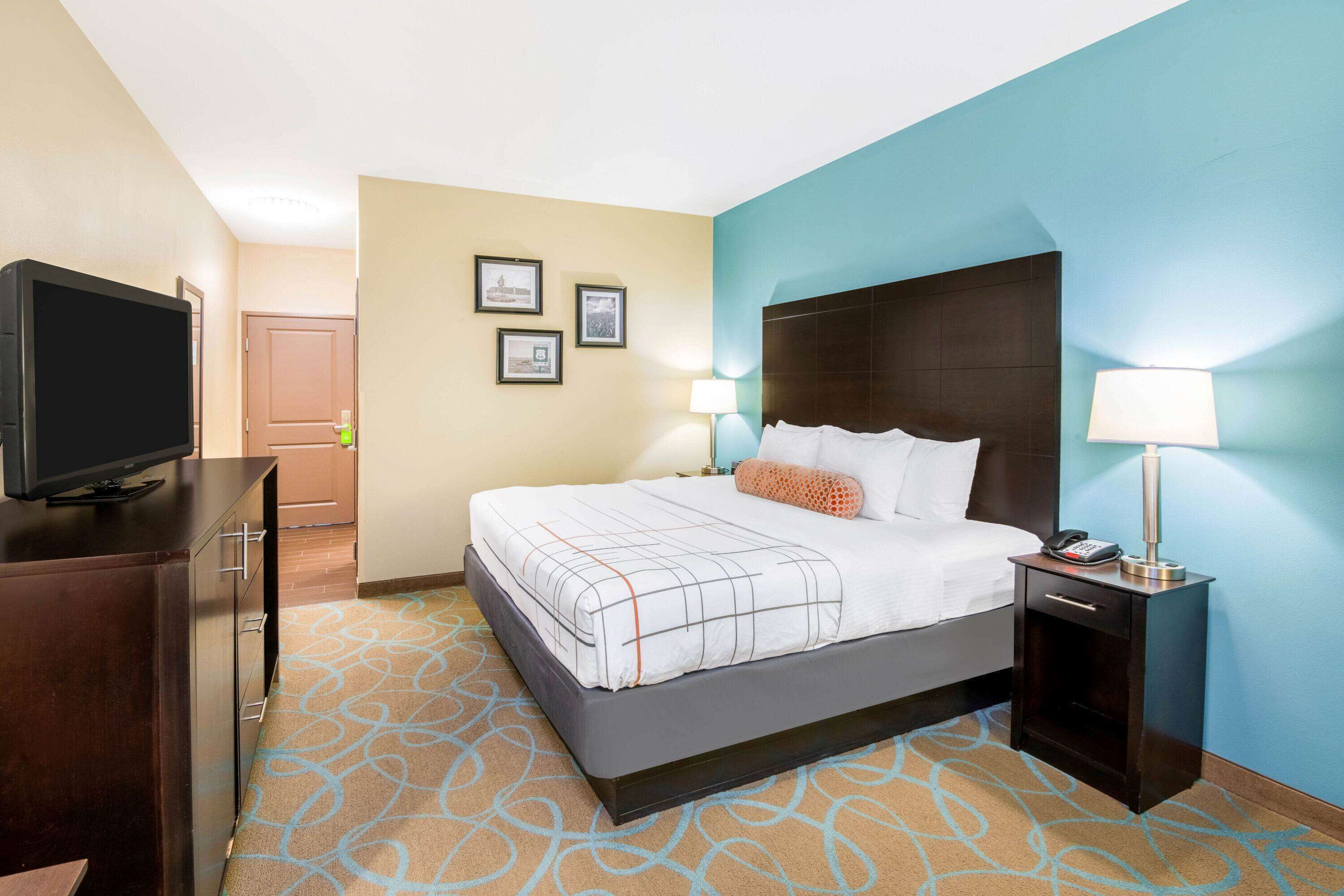 A hotel room with a bed, a TV, a desk, and a lamp.