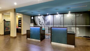 Un espace d’accueil avec un plafond bleu, un mur décoré d’éoliennes et l’inscription « voyez le bon côté des choses », ainsi qu’un réfrigérateur rempli de boissons.