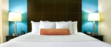 A hotel room with a large bed, two bedside tables, a telephone, and a nightstand with a lamp.