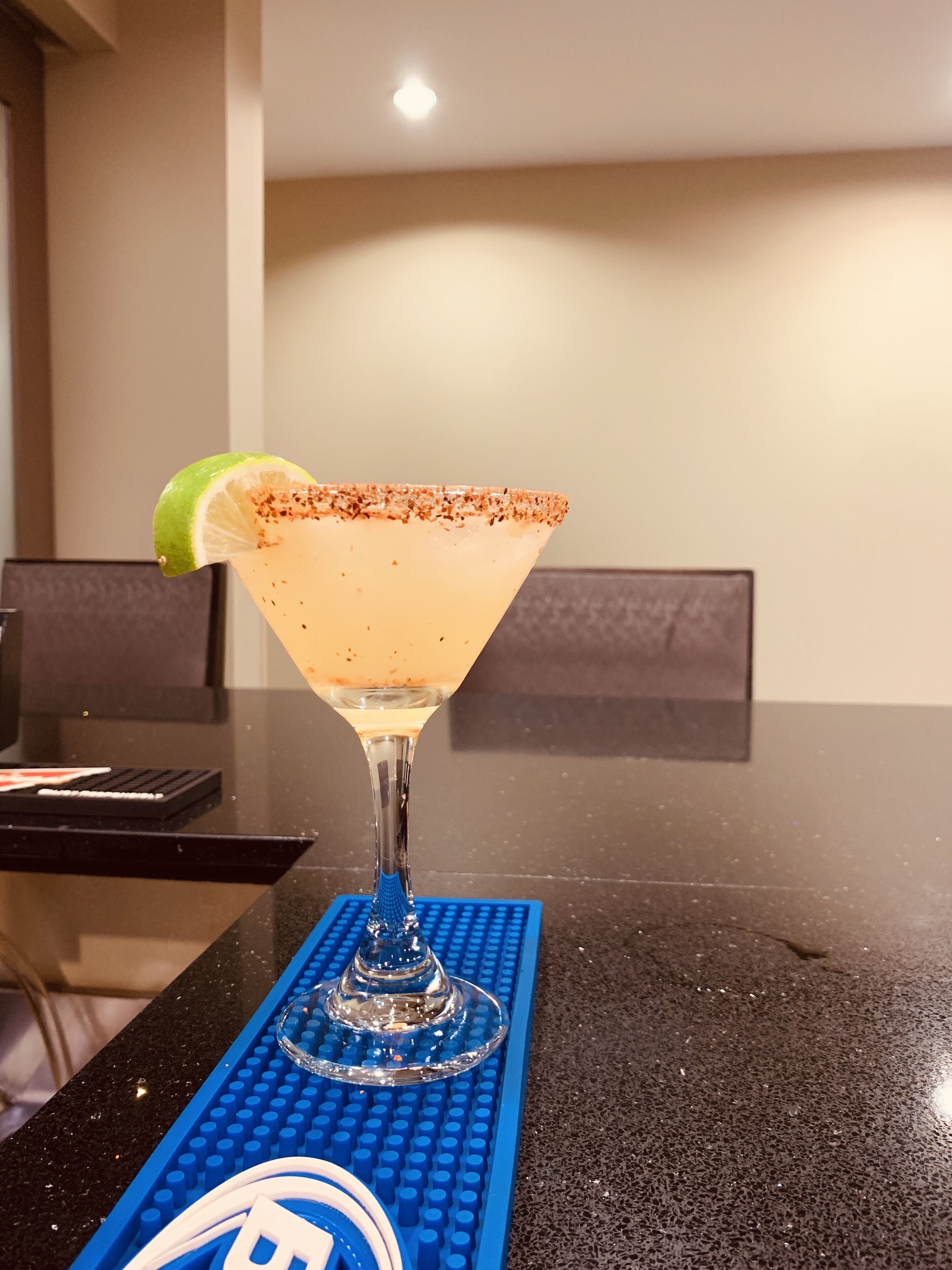 Un margarita su una base blu LEGO, guarnito con una fetta di lime, appoggiato su un bancone nero.