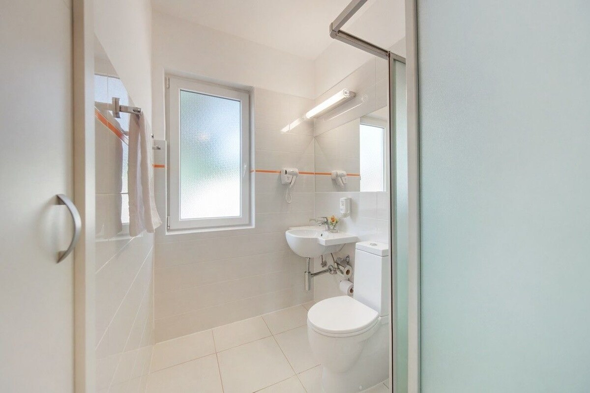 Un baño moderno con inodoro, lavabo y cabina de ducha con mampara de vidrio.