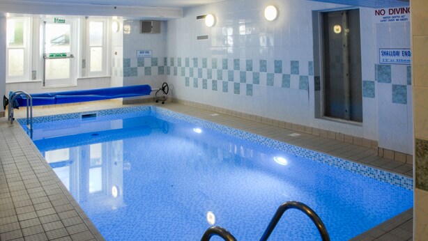 An indoor swimming pool with a blue tiled floor, a shallow end, and a no diving sign. - New Westcliff Hotel (Bournemouth)