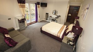 A bedroom with a bed, a desk, a chair, a wardrobe, a TV, and a balcony with curtains. - New Westcliff Hotel (Bournemouth)