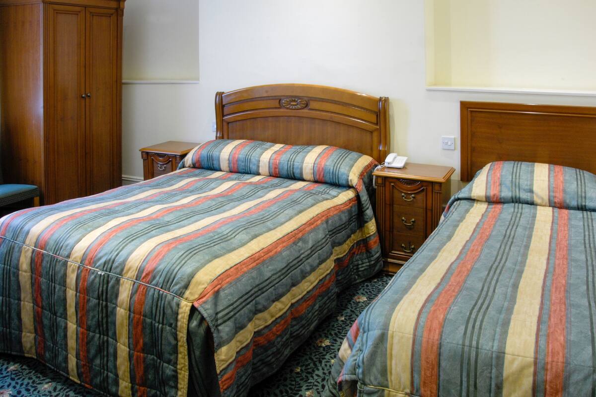 Ein Doppelbett mit gestreifter Bettwäsche, ein Holz-Kopfteil und ein Nachttisch mit Telefon.
