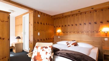 Una habitación con paneles de madera, una cama, dos lámparas de noche y una silla con un cojín estampado con vacas.