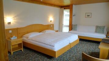 A hotel room with a wooden ceiling, a large bed with a wooden headboard, a smaller bed, a nightstand with a lamp, and a chair.