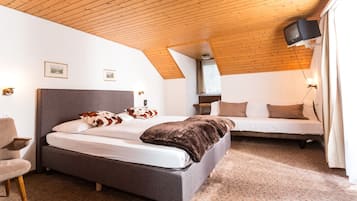 A bedroom with a large bed, a smaller bed, a chair, and a television.