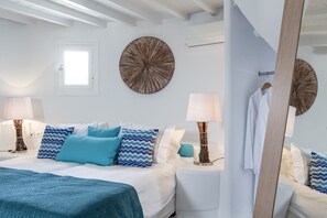 Quarto de hotel com uma cama, duas mesas de cabeceira, uma janela e decoração nas paredes.