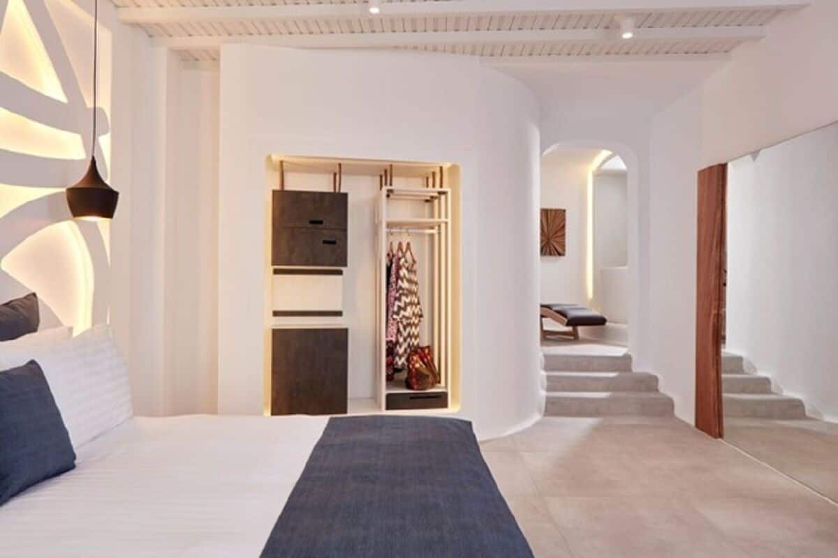 Une chambre d’hôtel moderne équipée d’un lit, d’un dressing et d’un escalier menant à un autre espace.