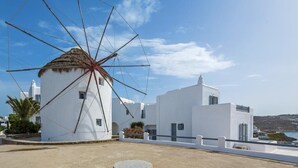 A windmill with a white building in the background. - Absolute Mykonos Suites & More (Mykonos)