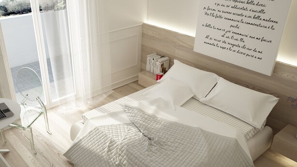 Un dormitorio moderno con una cama grande, una mesita de noche con una computadora portátil y vistas al exterior a través de una ventana.